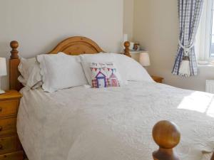 Gileston1-Bed Cottage on Coastal Pathway in South Wales的卧室配有一张带白色床单和枕头的大床。