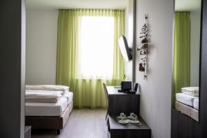 Neupirkaeee Hotel Graz的客房设有两张床和一个带绿色窗帘的窗户。
