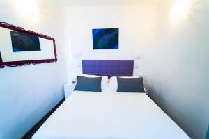 卡塔尼亚埃特纳套房旅馆的一间卧室配有一张白色大床和紫色床头板