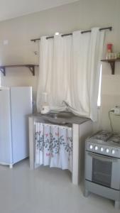 卡博迪圣阿戈斯蒂尼奥Kitnet 1,Vista fantastica的小厨房配有炉灶和白色窗帘