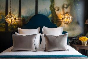 巴黎Hôtel Vinci Due & Spa的一间卧室配有带枕头的床铺和绘画