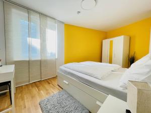 维也纳Topmodernes Sonnenwohnen Apartment bei U-Bahn und Therme Wien Oberlaa, 15 min bis Stephansplatz的一间卧室设有黄色的墙壁和一张带书桌的床。