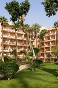 卢克索卢克索帕维隆冬季索菲特酒店的一座大型公寓楼,公园内种有棕榈树