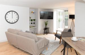 哈罗盖特The Burrow by Harrogate Serviced Apartments的客厅配有沙发和墙上的时钟