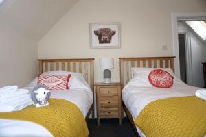 金洛赫兰诺赫Kinloch Rannoch Holiday Cottage的卧室配有两张床,床上有一只奶牛