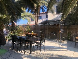 弗龙蒂尼昂FLAMANTS ROSES 2的庭院配有桌椅和遮阳伞。