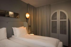 利勒哈默尔斯堪迪克维多利亚酒店的卧室配有白色的床和拱形窗户