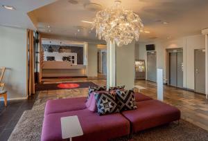 哈尔斯塔斯堪迪克哈尔斯塔酒店的客厅配有紫色沙发和吊灯。