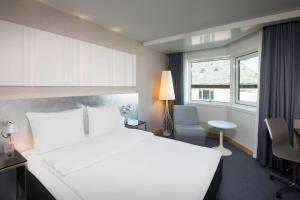 斯塔万格Scandic Royal Stavanger的卧室配有白色的床、书桌和窗户。