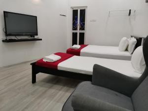 巴力拉惹RoomStay Hj Esmon Parit Raja UTHM的一张沙发和一台电视机的客房内的两张床