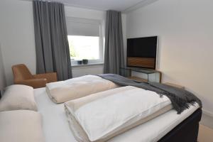 弗伦斯堡fewo1846 - FoerdeView - luxuriöse Wohnung mit 2 Schlafzimmern und Balkon mit Hafenblick的一间卧室配有两张床和一台平面电视