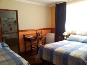 瓦拉斯科隆巴酒店的一间卧室设有两张床、一张桌子和一个窗口。