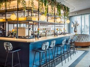 斯海弗宁恩Fletcher Hotel-Restaurant Scheveningen的酒吧餐厅里,有蓝色酒吧凳子