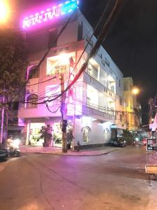 芹苴慧茵特兰酒店的街上的一座建筑,晚上有紫色的灯光