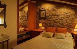Torre de FontaubellaCasa Rural LEra的一间卧室设有一张床和石墙