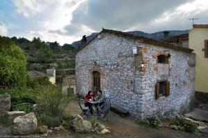 Torre de FontaubellaCasa Rural LEra的两个人坐在石头建筑外的桌子上