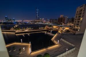 迪拜Suha Creek Hotel Apartment, Waterfront Jaddaf, Dubai的享有河面的夜间美景,设有一座桥