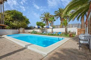 布埃纳维斯塔德尔诺尔特2 bedrooms house with shared pool enclosed garden and wifi at Buenavista del Norte 1 km away from the beach的一个带椅子的游泳池,棕榈树