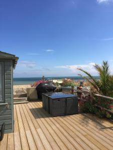 佩文西Beautiful 4 Bed Beach House的海滩上带桌子的木甲板
