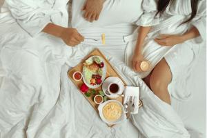艾因苏赫纳Cancun Sokhna Resort & Villas的两人睡在床上,带一个食物盘