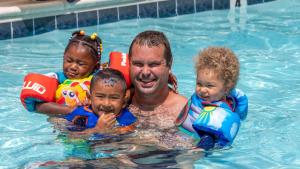 大洋城赤脚邮递员旅馆的游泳池里的一个男人和两个孩子