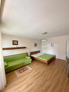 大梅杰尔Apartmánový dom Flóra的一间设有绿色沙发和一张床的客房