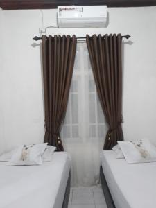 PainanBUMiMi HOMESTAY的配有棕色窗帘的客房内的两张床