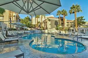 拉斯维加斯沙漠玫瑰度假酒店的一个带椅子和遮阳伞的度假村游泳池