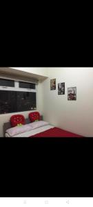 马尼拉Urban Deca Tower @ Graceysplace Unit 4 Mandaluyong的一间卧室配有两张带红色枕头的床和窗户。