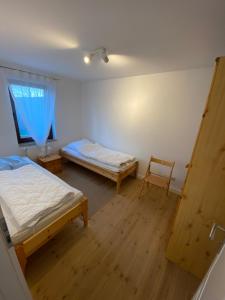 因塞尔波埃尔Insel-Poel-Ostseeurlaub de的客房设有两张床、一把椅子和窗户。