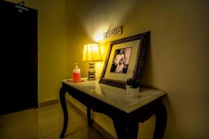 斋浦尔The Umaid Vilas Royal Heritage Haveli的一张桌子,上面有台灯,一张照片和一盏灯