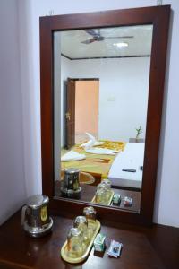 AmbalapulaiRamanilayam Tourist Home的一张桌子上的镜子,一张床上