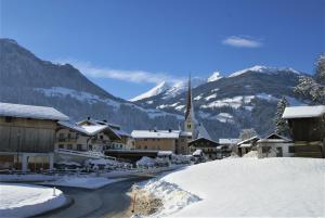 乌登斯All Inclusive Hotel Bachmayerhof的一座白雪覆盖的村庄,山上有一座教堂