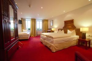 罗滕堡希尔施罗腾堡高登纳酒店的酒店客房,设有两张床,铺有红地毯。
