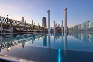 塞维利亚蒙泰特里亚纳酒店的一个带椅子的游泳池,一个城市背景