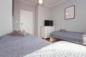 比亚韦斯托克CR Apartament Centrum Zamenhofa 1的一间卧室配有两张床、一台电视和一个梳妆台。