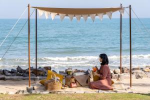 七岩Devasom Hua Hin Resort的坐在海滩上看着大海的女人