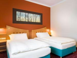 因戈尔施塔特美居因戈尔施塔特酒店的橙色墙壁客房的两张床