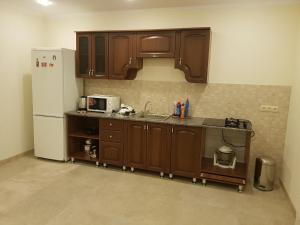 苏呼米Домик из двух комнат + кухня столовая с удобствами, со своим двориком под ключ的厨房配有木制橱柜和白色冰箱。