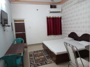 Kushinagarvindhyvasini guest house的小房间设有两张床和一张桌子及椅子