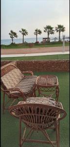 艾因苏赫纳Chalet Porto South Beach - Beach Front Sea View的两把柳条椅和一张桌子在海洋前