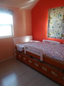 恵那市富田旅馆的一间卧室拥有橙色的墙壁、一张床和窗户