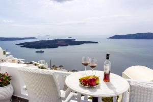 菲罗斯特法尼Santorini View Studios - Firostefani Caldera的一张桌子,上面放着两杯葡萄酒和一碗水果