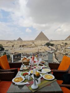 开罗Hayat Pyramids View Hotel的一张桌子,上面有食物,后面有金字塔
