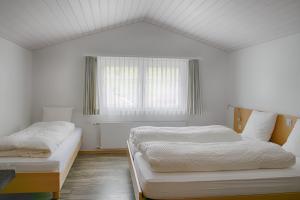 韦斯巴德Loosmühle的一间白色卧室,配有两张床和窗户