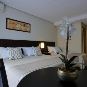 格拉玛多Hotel Querência的一间酒店客房,配有一张床铺和一张带花卉的桌子