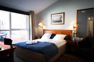 海松Hotel Møllehuset的一间卧室配有一张带蓝色毯子的床和窗户。