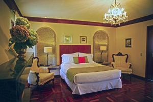 圣何塞特拉萨斯德高尔夫精品酒店的一间卧室配有一张床、两把椅子和一个吊灯