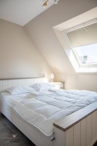奥斯坦德Spacious apartment in the heart of Ostend near the sea的卧室配有一张白色大床和天窗