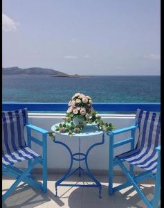 考弗尼西亚Hotel Posidonion的阳台上配有两把椅子和一张带鲜花的桌子